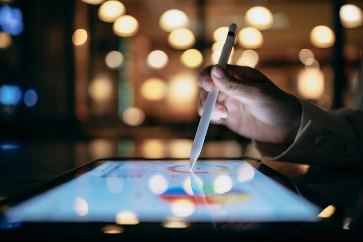 una mano señala con un lapiz sobre una tablet